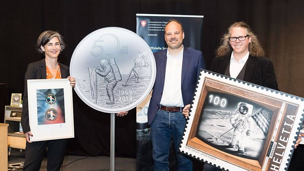 50 Jahre Mondlandung: Nicola von Greyerz von der Uni Bern zeigt das Jubiläumssignet der Hochschule, Christoph Tanner von Swissmint die Sondermünze und Bernhard Kallen von der Post die Sondermarke.