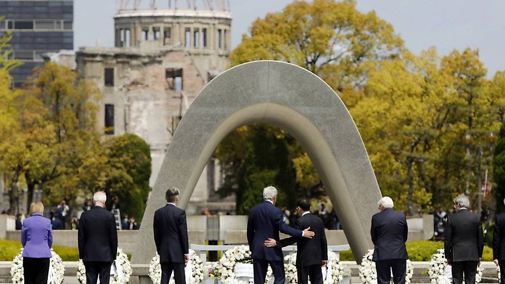 US-Aussenminister John Kerry (Mitte) legt vor dem Mahnmal zum US-Atombomben-Abwurf auf Hiroshima seinen Arm um seinen japanischen Amtskollegen Fumio Kashida.