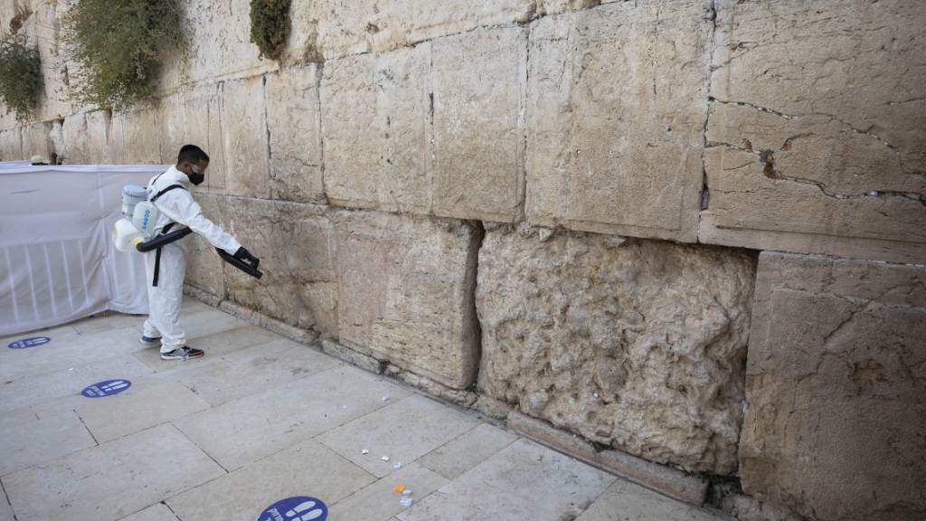 dpatopbilder - Ein Arbeiter verteilt Desinfektionsmittel als Vorsichtsmaßnahme gegen das Coronavirus an der Klagemauer, der heiligsten Stätte, an der Juden in Jerusalem beten können. Foto: Sebastian Scheiner/AP/dpa
