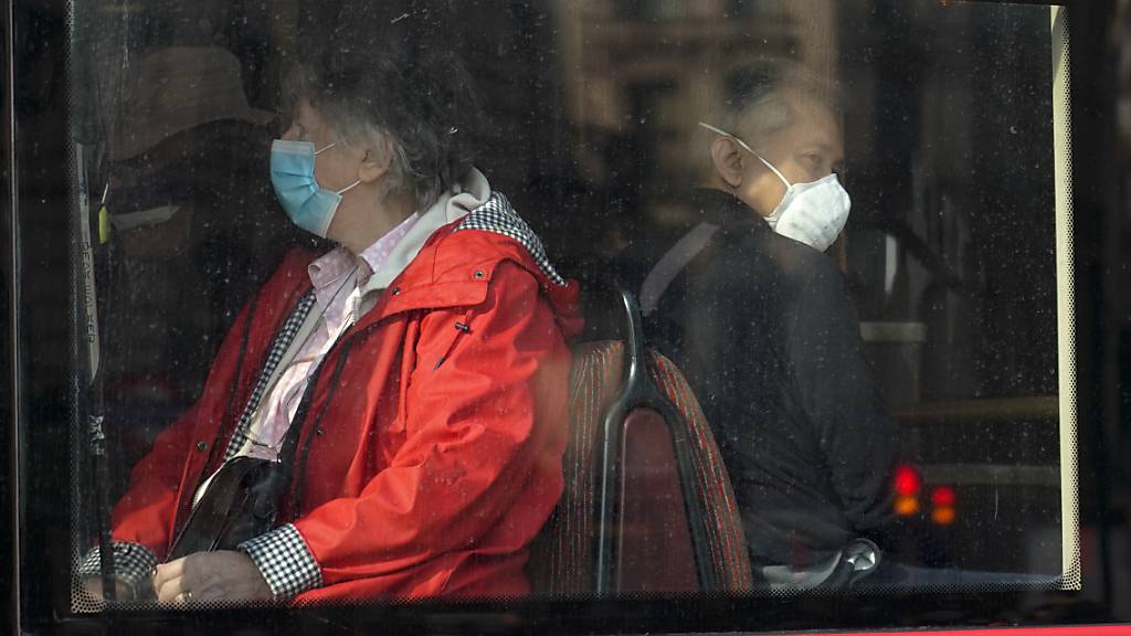 Menschen tragen Mund-Nasen-Schutz, während sie in einem Bus in London sitzen. Foto: Alberto Pezzali/AP/dpa