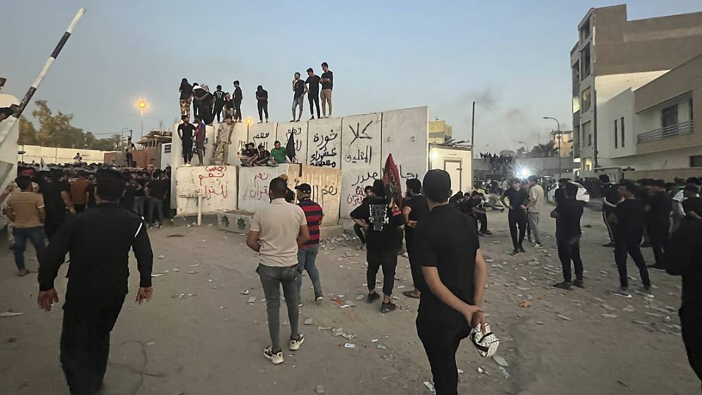 Demonstranten erklimmen eine Mauer an der schwedischen Botschaft. Foto: Ali Jabar/AP/dpa