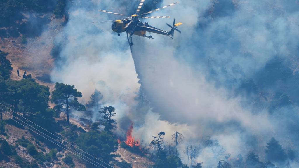 dpatopbilder - Ein Löschhubschrauber wirft Wasser über einen Waldbrand auf dem Berg Kithairon in der Nähe von Porto Germeno nordwestlich von Athen ab. Die Wald- und Buschbrände westlich der griechischen Hauptstadt sind noch nicht unter Kontrolle. Foto: Petros Giannakouris/AP/dpa