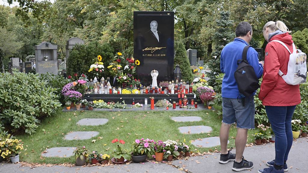Menschen stehen am Grab des tschechischen Sängers Karel Gott auf dem Malvazinky-Friedhof, wo frische Blumen stehen und Kerzen brennen. Vor einem Jahr, am 1. Oktober 2019, war der Sänger im Alter von 80 Jahren gestorben. Foto: Michael Heitmann/dpa