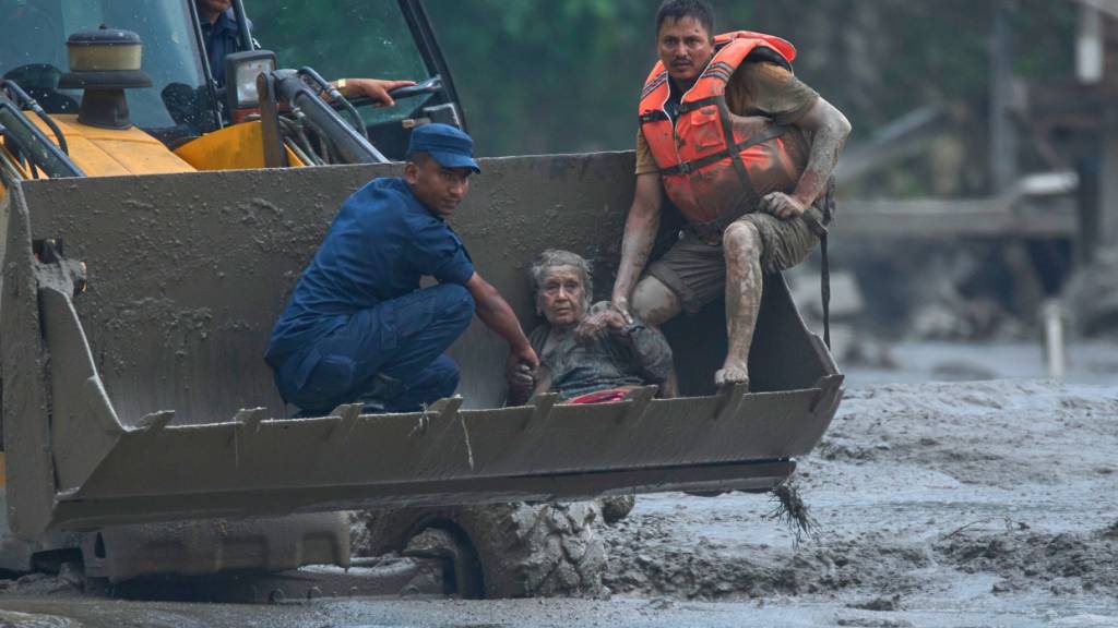 Rettungskräfte setzen am Trishuli-Fluss im nepalesischen Distrikt Nuwakot einen Radlader ein, um ein Opfer einer Sturzflut in Sicherheit zu bringen. Foto: Niranjan Shrestha/AP/dpa
