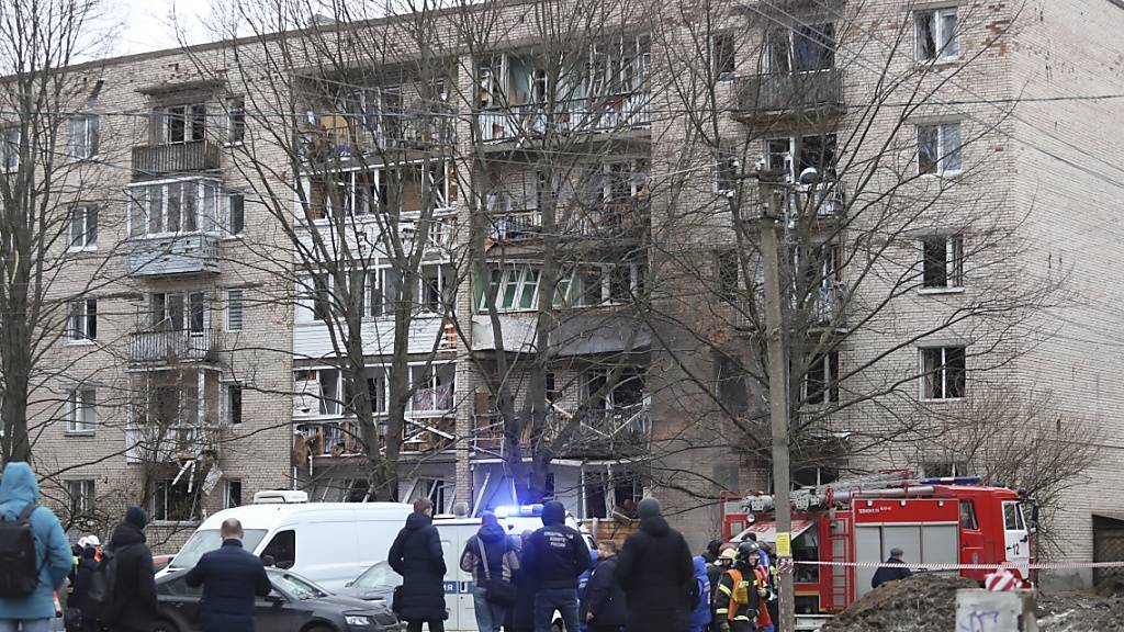 Menschen beobachten, wie Rettungskräfte nach einer Explosion an der Seite des beschädigten Wohnhauses in Sankt Petersburg arbeiten. Foto: Uncredited/AP