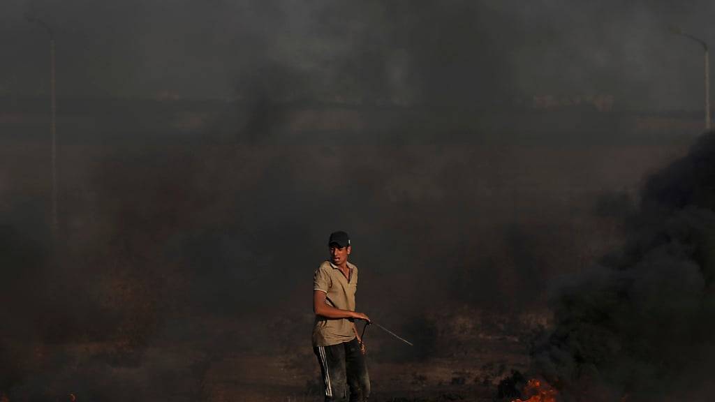 Ein palästinensischer Demonstrant verbrennt Reifen während Zusammenstößen mit israelischen Sicherheitskräften. Bei neuen Konfrontationen mit Soldaten an der Grenze zu Israel ist im Gazastreifen mindestens ein Palästinenser getötet worden. Foto: Adel Hana/AP/dpa