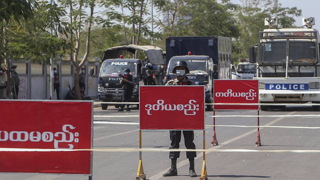 Polizisten stehen Wache auf einer abgesperrten Straße in Mandalay. Foto: Str/AP/dpa