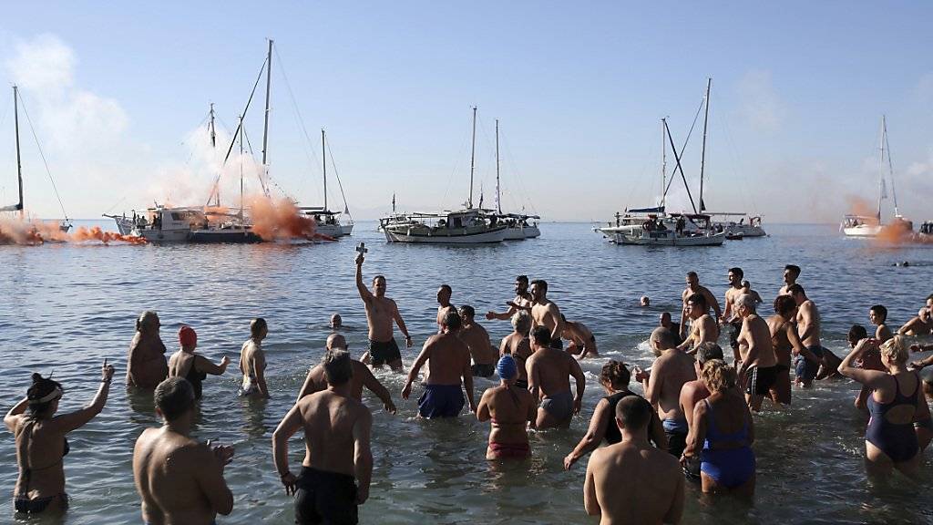 Eine Gruppe griechisch-orthodoxer Christen feiert die Taufe Jesu - der Glücklich, der das Kreuz im Wasser gefunden hat, soll im neuen Jahr bessere Chancen auf Glück und Gesundheit haben.
