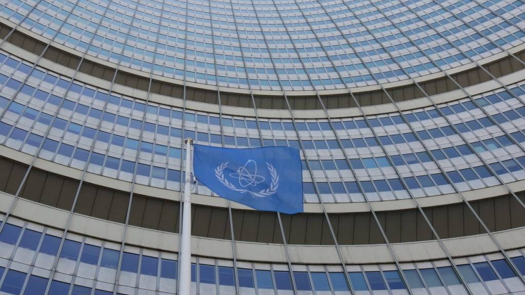 ARCHIV - Eine Flagge weht vor dem Hauptquartier der Internationalen Atomenergiebehörde (IAEA). Der Chef der IAEA (International Atomic Energy Agency), Grossi, hatte Israel vor einem Angriff auf iranische Atomanlagen gewarnt. Jetzt hat Grossi den Angriff auf Irans Atomprogramm verurteilt. Foto: Albert Otti/dpa