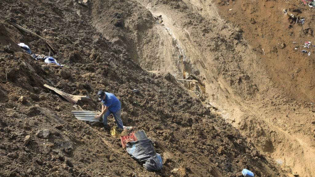 Ein Mann sammelt seine Habseligkeiten ein, nachdem ein tödlicher Erdrutsch durch starke Regenfälle in der kolumbianischen Gemeinde Bello ausgelöst wurde. Foto: Fredy Amariles/AP/dpa