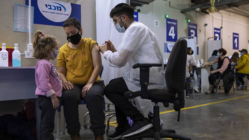 Eine israelische Frau bekommt von einer medizinischen Fachkraft in einem Impfzentrum eine Impfdosis mit dem Corona-Impfstoff von Biontech/Pfizer. Foto: Oded Balilty/AP/dpa