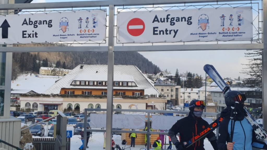 Skifahrer gehen in Semmering unter Schildern, die auf die coronabedingten Hygieneregeln hinweisen, durch. Foto: Semmering-Hirschenkogel Bergbahn/APA/dpa