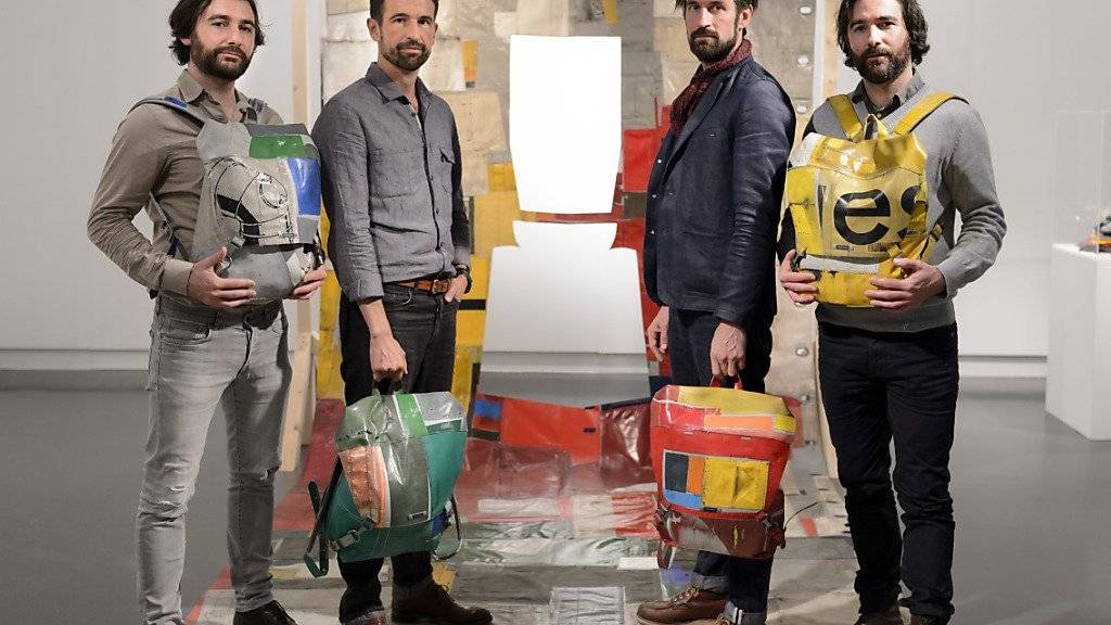 Auf der «re-recycelten» LKW-Plane zeigen Frank Riklin, Markus Freitag, Daniel Freitag und Patrik Riklin (v.l.n.r.) die Rucksäcke zum Ausleihen im Design-Museum mudac in Lausanne.