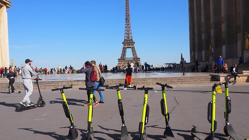 ARCHIV - E-Tretroller stehen zum Mieten auf der Place du Trocadero bereit - im Hintergrund ist der Eiffelturm zu sehen. Das Tempo von E-Scootern wird in Paris von den drei großen Vermietern seit Montag in Teilen des Zentrums auf Tempo 10 gedrosselt. Foto: Christian Böhmer/dpa