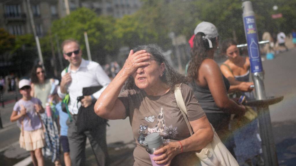 Touristen erfrischen sich an einem öffentlichen Trinkbrunnen in Paris. Foto: Christophe Ena/AP/dpa/Archivbild