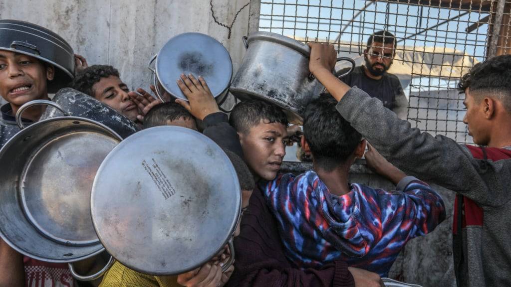 ARCHIV - Palästinenser stehen an, um eine Mahlzeit vom Welternährungsprogramm und dem Hilfswerk der Vereinten Nationen für Palästinaflüchtlinge im Nahen Osten (UNRWA) zu erhalten. Die Vereinten Nationen und internationale Organisationen warnen vor einer Hungersnot im Gazastreifen und fordern alle Konfliktparteien, die palästinensischen Gruppierungen und die israelische Regierung auf, die Einfahrt von Hilfslieferungen in den Gazastreifen zu gestatten und ihre Einsätze zu erleichtern, um eine humanitäre Katastrophe im Gazastreifen aufgrund des Konflikts zwischen Israel und der Hamas zu verhindern. (zu dpa: «USA und Israel wollen Gaza-Hilfe an Hamas vorbei liefern») Foto: Abed Rahim Khatib/dpa