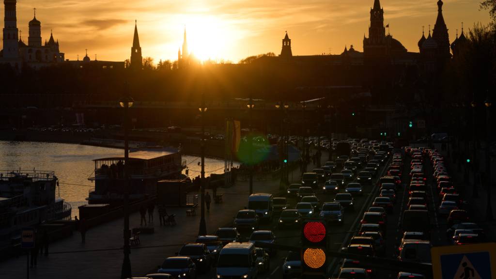 Autos fahren bei Sonnenuntergang am Moskvoretskaya-Ufer des Moskwa-Flusses entlang, im Hintergrund der Kreml. Foto: Alexander Zemlianichenko/AP/dpa