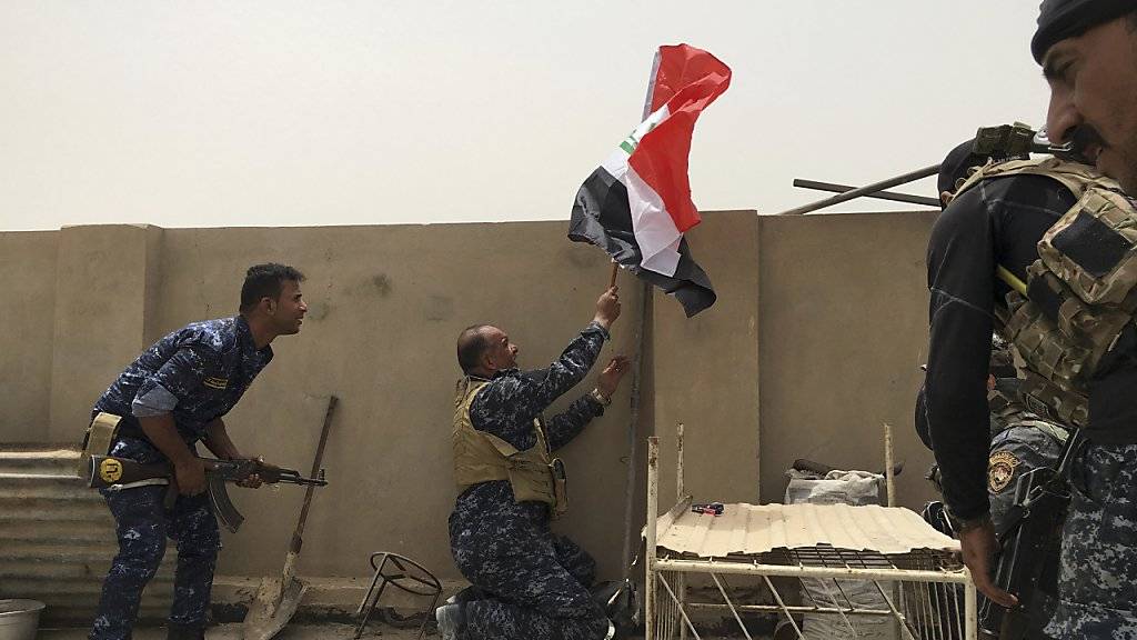 Irakische Sicherheitskräfte halten eine irakische Flagge in Falludschah hoch - die Stadt bleibt umkämpft.