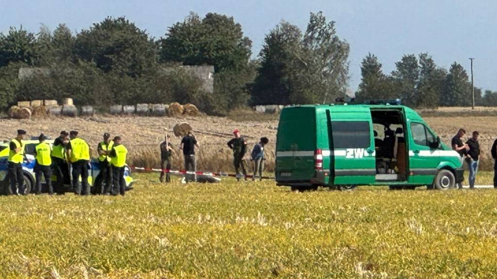 Polizei und Militärpolizei sichern Teile einer beschädigten Drohne, die von polnischen Behörden abgeschossen wurde, auf einem Gelände in Wohyn. Foto: Rafal Niedzielski/AP/dpa