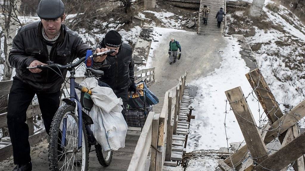 Ostukrainer gehen über eine improvisierte Brücke in der Nähe von Luhansk. Der Konflikt in der Ostukraine belastet den Alltag der Einwohner immer noch stark, laut der UNO. (Archiv)
