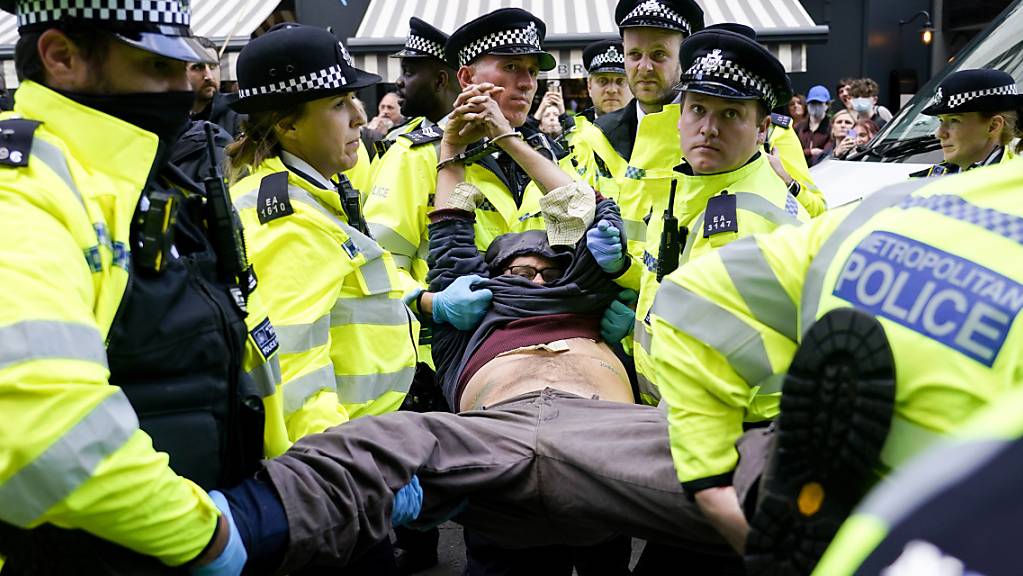 Polizisten verhaften einen Demonstranten, der sich während eines von der Umweltschutzbewegung Extinction Rebellion organisierten Protests unter einen Lieferwagen klebte. Bei der Protestaktion in London laut Mitteilung von Scotland Yard am späten Montagabend mehr als 50 Menschen festgenommen worden. Foto: Alberto Pezzali/AP/dpa