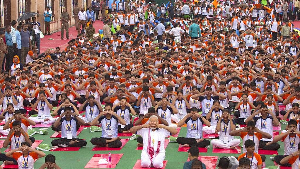 Der indische Premierminister Narendra Modi (Mitte, kniend) macht zusammen mit tausenden andern in Lakhnau Yoga-Übungen zum Weltyogatag.