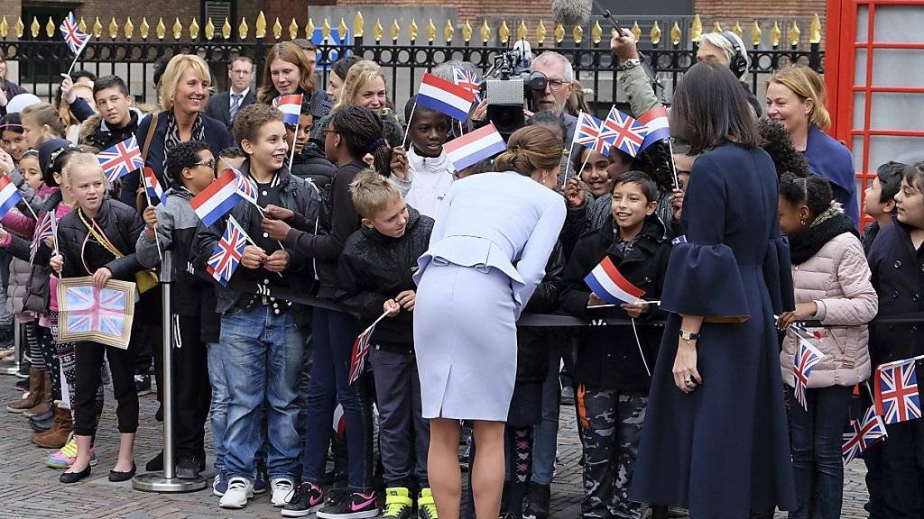 Herzogin Kate redet mit Kindern, die sie mit niederländischen und britischen Fähnchen vor dem Mauritshuis Museum empfangen haben.