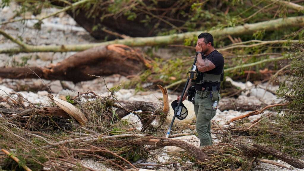 Ein Hilfssheriff hält inne, während er die Ufer des Guadalupe River in der Nähe von Camp Mystic durchkämmt, nachdem eine Sturzflut in Hunt, Texas, über das Gebiet hinweggefegt ist. Foto: Julio Cortez/AP/dpa