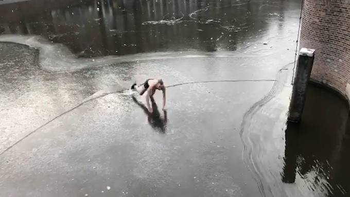 Schlittschuhläufer fällt halbnackt in zugefrorenen Kanal