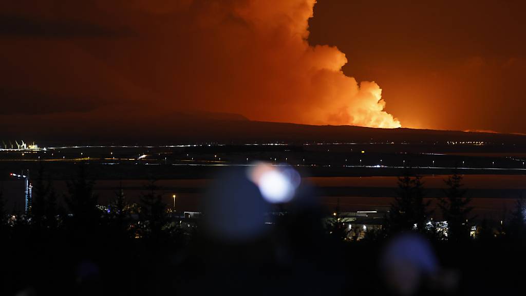 Menschen beobachten, wie der Nachthimmel nach dem Ausbruch eines Vulkans im Südwesten Islands erhellt wird. Foto: Brynjar Gunnarsson/AP