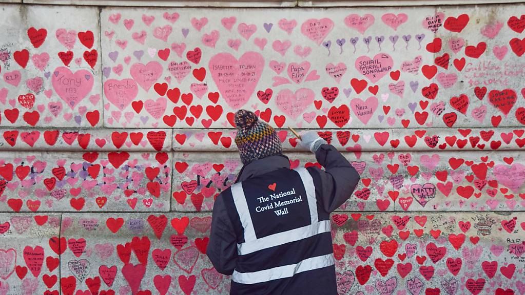 Ein Freiwilliger streicht die Herzen auf der National Covid Memorial Wall in London neu an. In Großbritannien hat die Zahl der Todesfälle nach einer mittels PCR-Test bestätigten Corona-Infektion die Marke von 150 000 überschritten. Das teilte das Gesundheitsministerium am Samstag mit. Foto: Vuk Valcic/SOPA Images via ZUMA Press Wire/dpa
