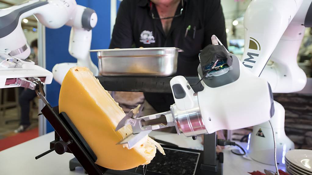 Ein Roboter streicht eine Portion Raclette auf einen Teller. Das Gerät wurde am Samstag an einer Messe in Martigny VS vorgestellt.