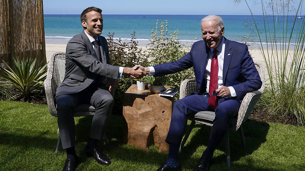 Joe Biden (r), Präsident der USA, und Emmanuel Macron, Präsident von Frankreich, schütteln sich die Hand bei einem gemeinsamen Treffen während des G7-Gipfels. Foto: Patrick Semansky/AP/dpa