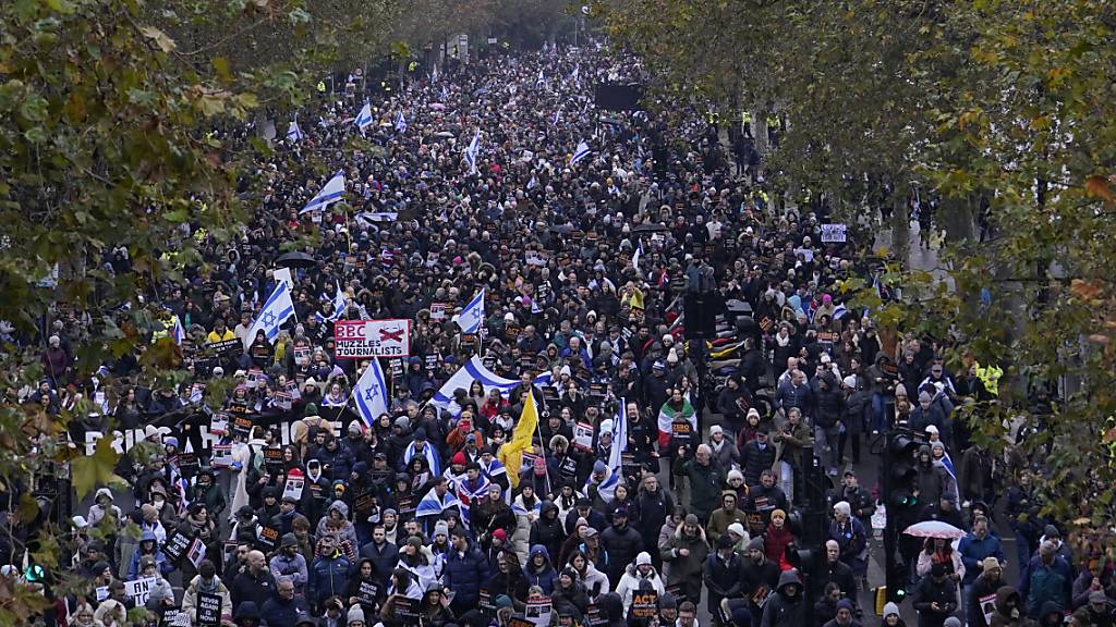Teilnehmer halten während einer Demonstration gegen Antisemitismus Plakate, Fahnen und Transparente. Foto: Alberto Pezzali/AP/dpa