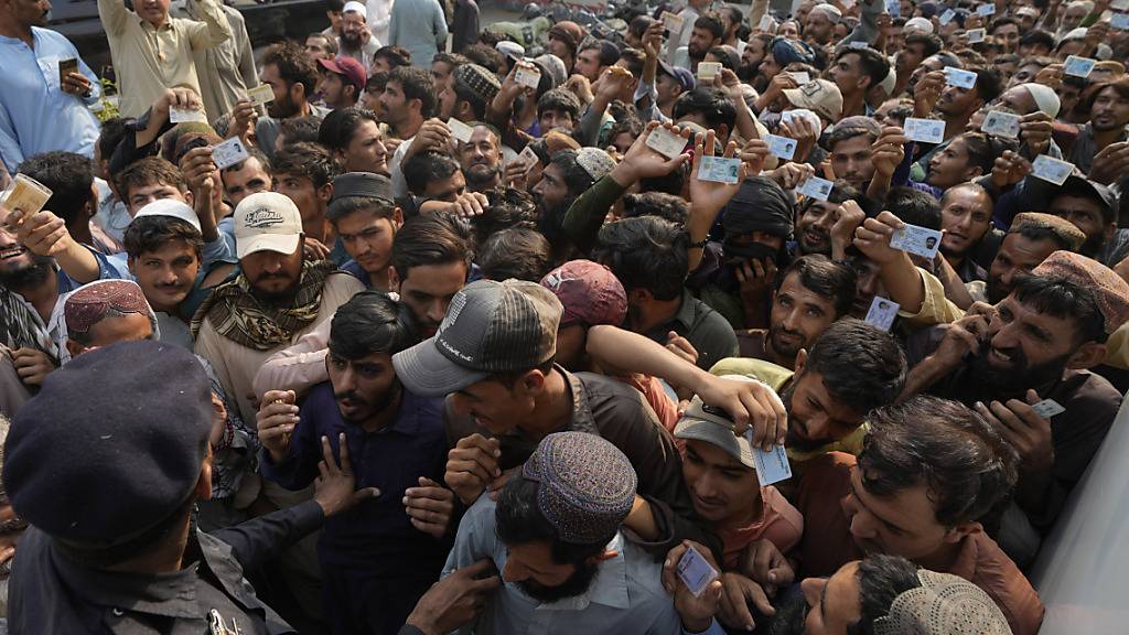 Polizeibeamte versuchen, Einwanderer zu kontrollieren, die sich an einem Schalter der pakistanischen Nationalen Datenbank- und Registrierungsbehörde versammelt haben. Der Londoner «Guardian» hat die Massenabschiebungen von afghanischen Flüchtlingen aus Pakistan kritisiert. Foto: Fareed Khan/AP/dpa