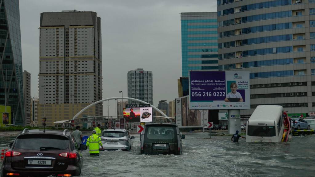 Fahrzeuge stecken nach heftigen Regenfällen auf einer überfluteten Straße fest, während ein Lieferwagen abgeschleppt wird. Foto: Uncredited/AP/dpa