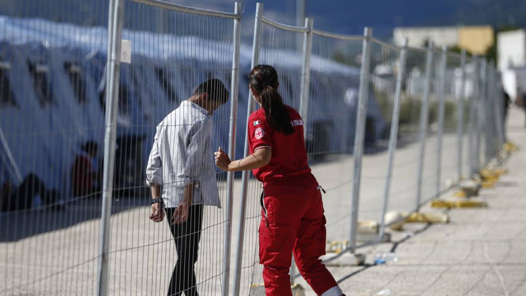 Ein geflüchteter Afghane geht an einem Zaun in einem Einsatzzentrum des italienischen Roten Kreuzes, Croce Rossa Italiana (CRI) in Avezzano. In dem Einsatzzentrum werden mit Hilfe der Armee und des Zivilschutzes afghanische Geflüchtete aufgenommen.
