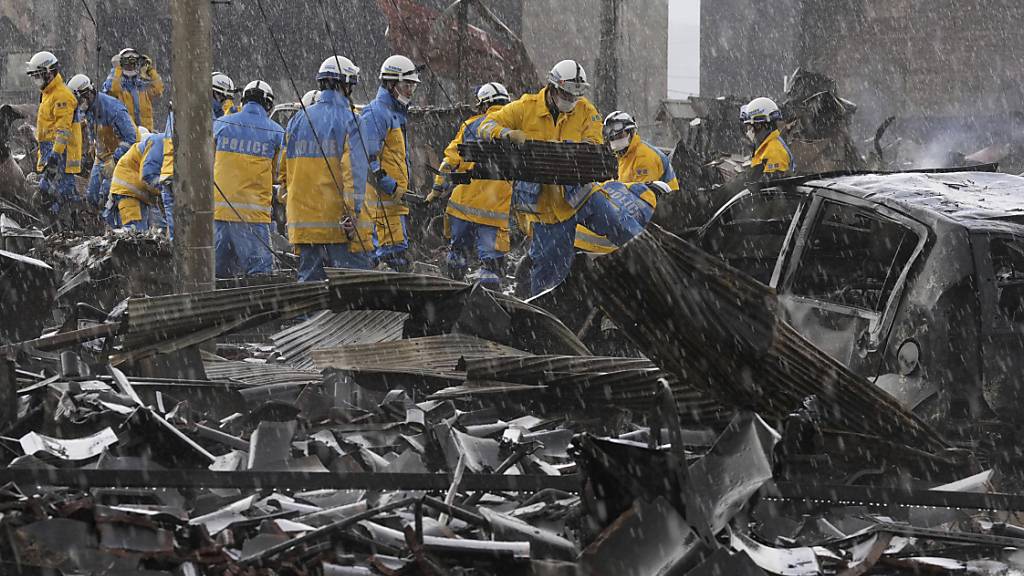 Polizeibeamte beseitigen die Trümmer eines Brandes auf einem Markt in der Präfektur Ishikawa. Foto: Uncredited/Kyodo News/AP/dpa - ACHTUNG: Nur zur redaktionellen Verwendung und nur mit vollständiger Nennung des vorstehenden Credits