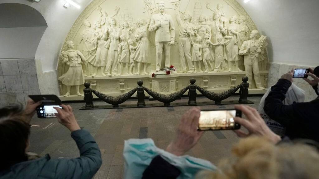 Menschen fotografieren das Stalin-Relief in Moskau. Foto: Pavel Bednyakov/AP/dpa