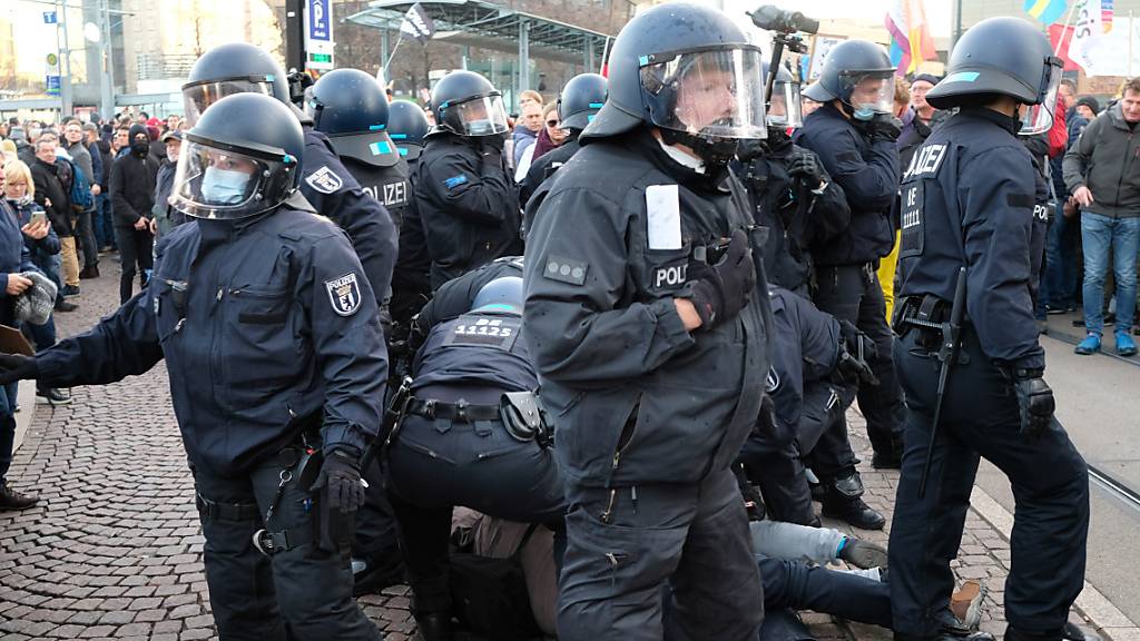 Polizisten nehmen während einer Kundgebung von Kritikern der Coronamaßnahmen der Bundesregierung eine Person in Gewahrsam. Foto: Sebastian Willnow/dpa-Zentralbild/dpa