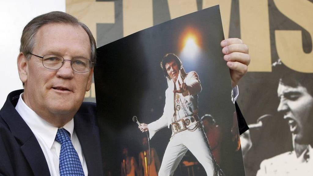 Der Elvis-Fotograf Ed Bonja posiert am 13. Aug. 2007 in Berlin mit einem Foto des «King of Rock ‹n› Roll» vor einem Ausstellungsplakat. Im September 2019 ist Bonja im Alter von 74 Jahren gestorben. (Archiv)