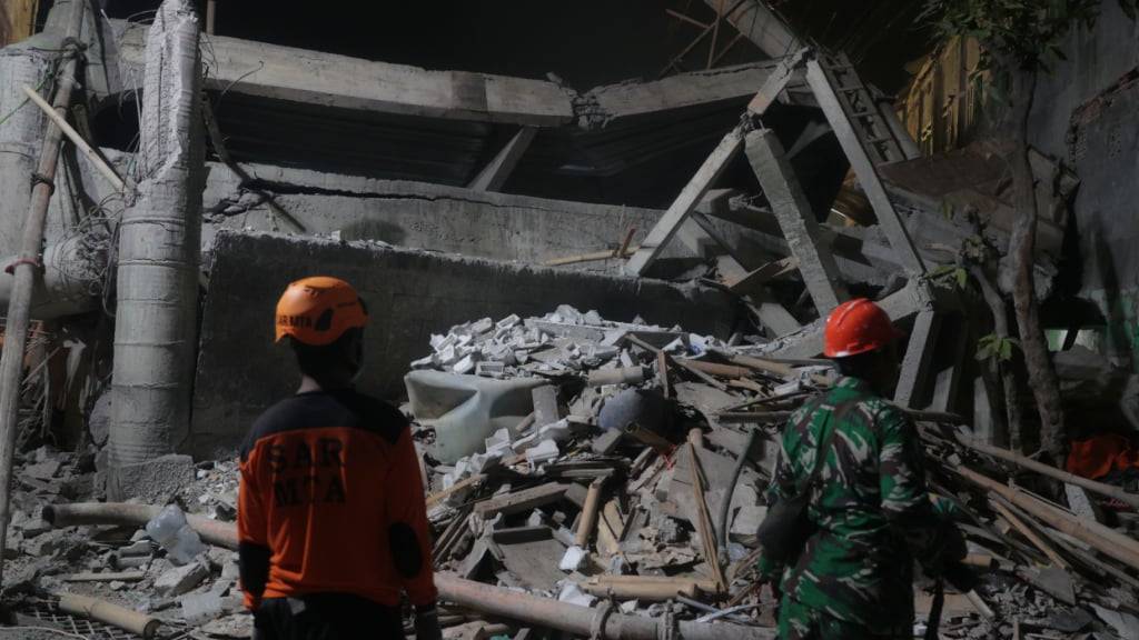 Rettungskräfte suchen nach dem Einsturz eines Gebäudes in einem islamischen Internat nach Überlebenden. Foto: Trisnadi/AP/dpa