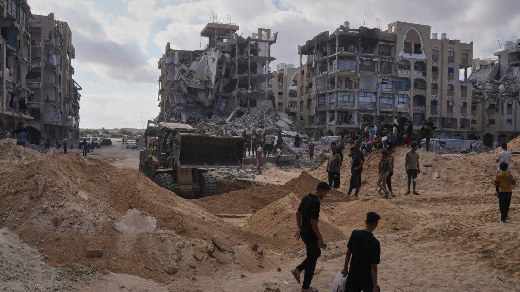 Palästinenser beobachten Mitglieder der militanten Hamas-Gruppe bei der Suche nach den Leichen der Geiseln in einem Gebiet in Hamad City, Chan Junis, im südlichen Gazastreifen. Foto: Jehad Alshrafi/AP/dpa