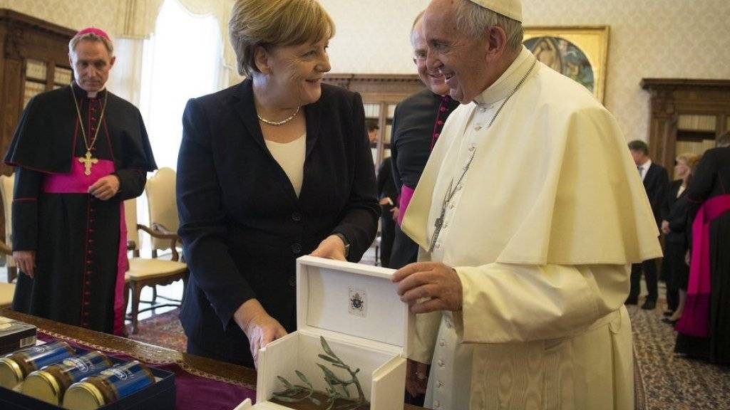Austausch der Geschenke nach der Audienz im Vatikan: Papst Franziskus (r.) überreicht der deutschen Kanzlerin Merkel (l.) unter anderem eine Medaille mit einem Olivenzweig.