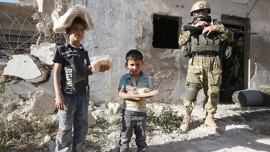 Syrische Kinder erhalten Brot und Süssigkeiten aus einer russischen Hilfslieferung in der Provinz Hama. Für die umkämpfte Stadt Aleppo hat das Regime einer Feuerpause zugestimmt.
