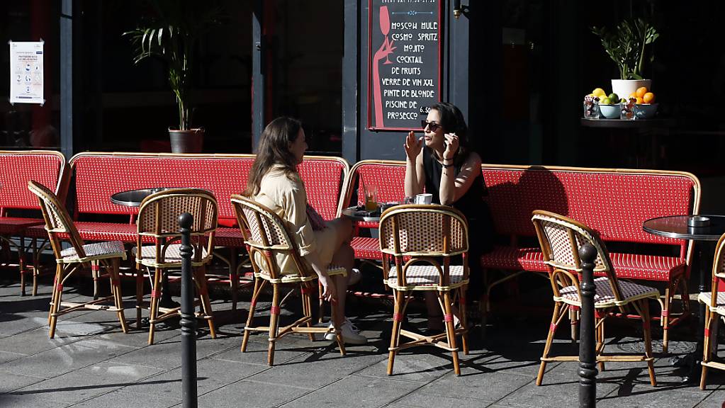 Zwei Frauen sitzen im Aussenbereich an einem Tisch einer Gastronomie. In Frankreich wurden weitere Lockerungen während der Corona-Pandemie durchgesetzt, so dass Restaurants und Cafés unter bestimmten Bedingungen nun wieder öffnen dürfen.