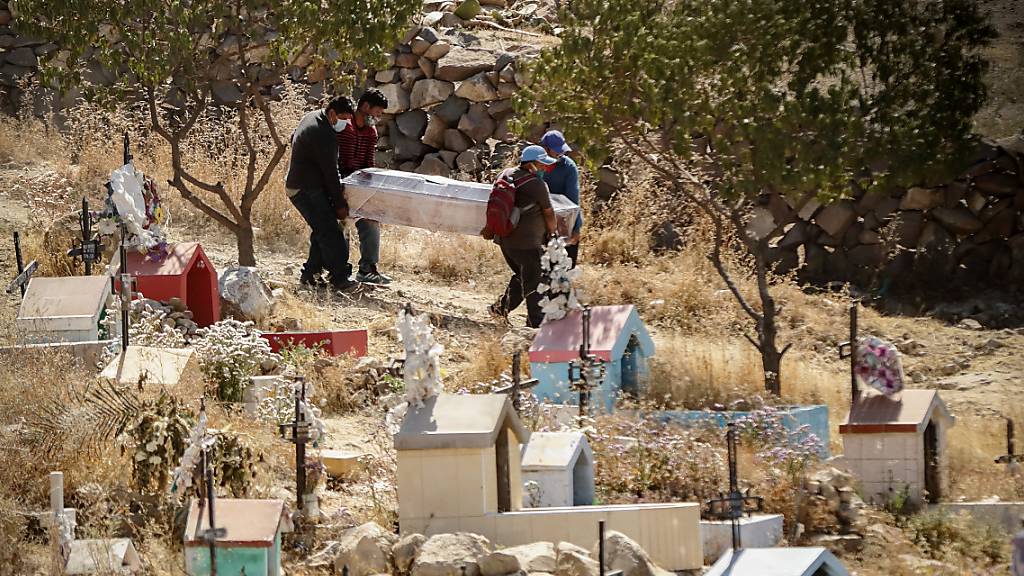 Menschen mit Mundschutzmasken tragen inmitten der Corona-Pandemie einen Sarg bei eine Beerdigung auf dem Friedhof El Cebollar in Peru.