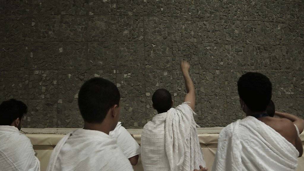 Saudiarabische Pilger werfen in Mina Steine gegen eine Säule und steinigen so symbolisch den Teufel.