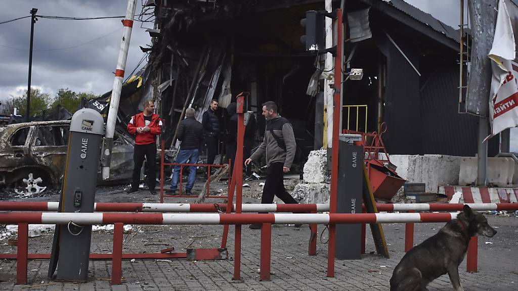 Menschen stehen an den durch den russischen Angriff beschädigten Gebäuden. Foto: Andriy Andriyenko/AP/dpa