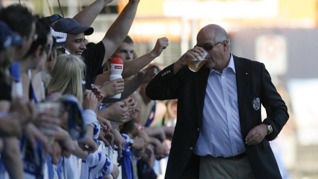 FCL-Präsident Walter Stierli bewacht am Match zwischen Luzern und Lugano 2009 die Fans und erhält von diesen ein Bier spendiert. (Archivaufnahme)